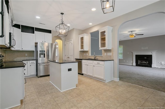 kitchen featuring appliances with stainless steel finishes, a sink, ceiling fan, arched walkways, and dark countertops