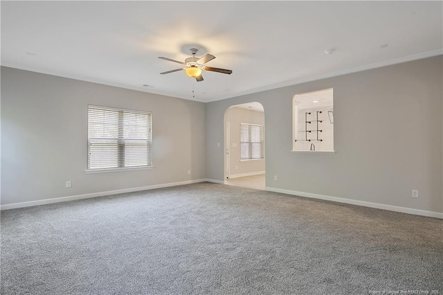 empty room featuring ceiling fan, baseboards, light colored carpet, and ornamental molding