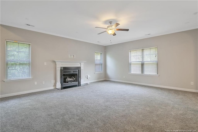 unfurnished living room with a ceiling fan, crown molding, carpet, baseboards, and a fireplace with flush hearth