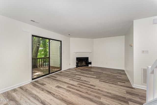 unfurnished living room with wood finished floors, a fireplace, and baseboards