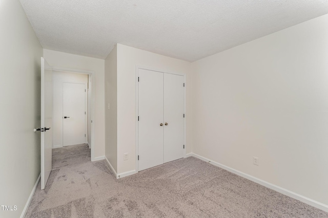unfurnished bedroom with carpet, baseboards, a closet, and a textured ceiling