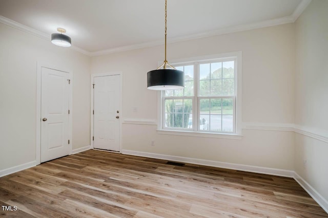unfurnished dining area featuring wood finished floors, crown molding, and baseboards