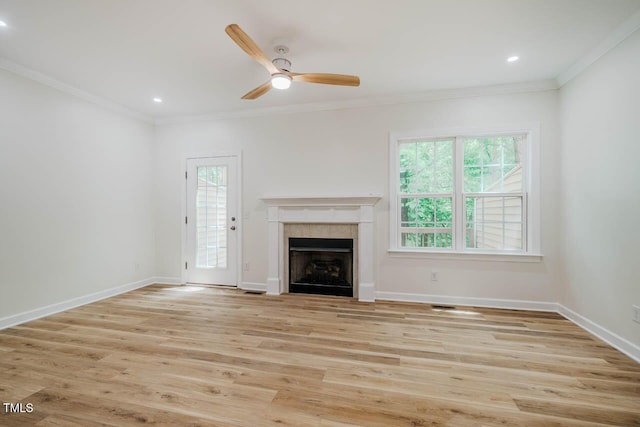 unfurnished living room with healthy amount of natural light, crown molding, baseboards, ceiling fan, and a tile fireplace