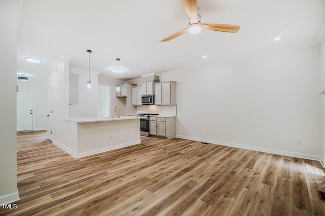kitchen with gas range, stainless steel microwave, light wood-type flooring, a sink, and a ceiling fan