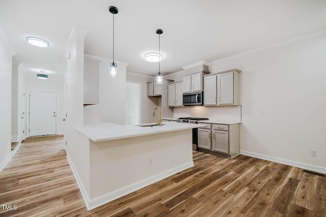 kitchen with appliances with stainless steel finishes, a sink, gray cabinets, light wood-style flooring, and ornamental molding