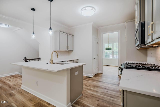 kitchen with a sink, stainless steel microwave, crown molding, a peninsula, and light wood-type flooring