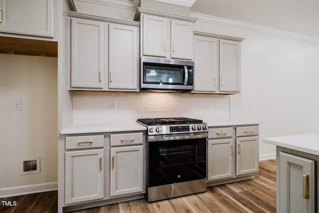 kitchen featuring stainless steel appliances, light wood-style floors, light countertops, and crown molding