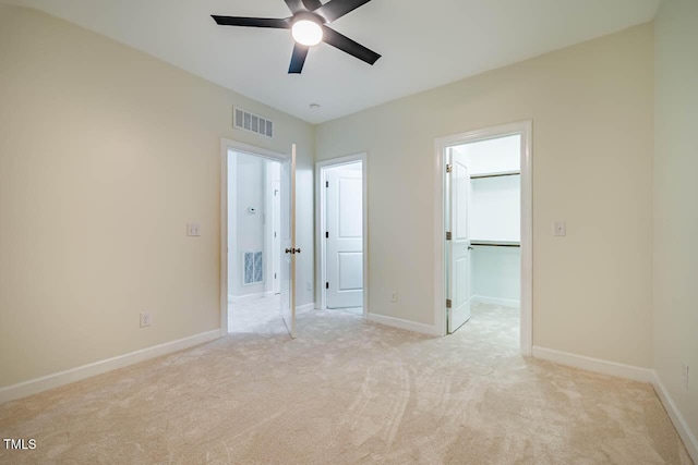 unfurnished bedroom featuring light colored carpet, baseboards, and a walk in closet