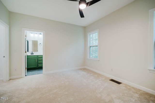 unfurnished bedroom featuring light colored carpet, a sink, baseboards, and connected bathroom