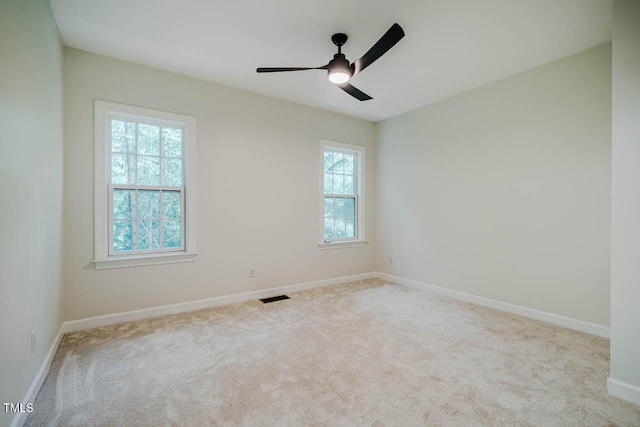 carpeted spare room featuring baseboards and a ceiling fan
