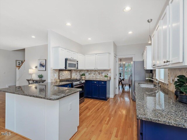 102 Westside Dr, Chapel Hill, NC 27516 - kitchen featuring stainless steel appliances, blue cabinets, a sink, white cabinets, and a peninsula