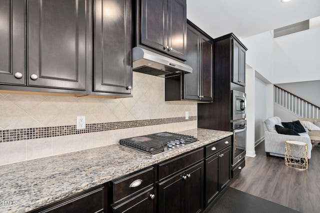 310 Alamosa Pl, Cary, NC 27519 - kitchen featuring stainless steel appliances, under cabinet range hood, light stone counters, backsplash, and dark wood-type flooring