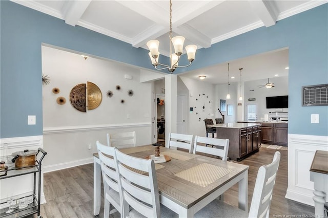 dining area with beam ceiling, coffered ceiling, wood finished floors, a chandelier, and a wainscoted wall