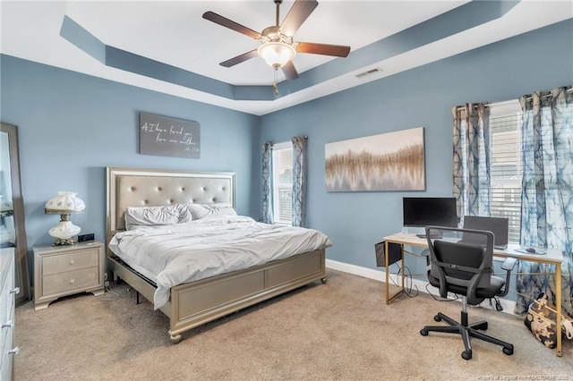 bedroom featuring a raised ceiling, carpet floors, a desk, baseboards, and ceiling fan