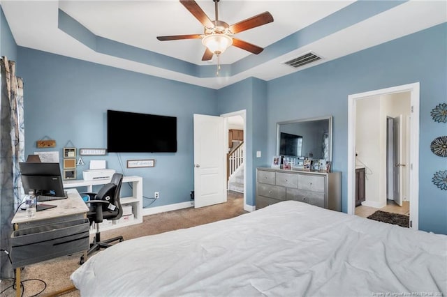 carpeted bedroom with a raised ceiling, baseboards, a desk, and a ceiling fan