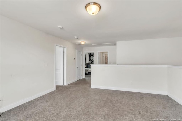 empty room with carpet floors, baseboards, and a smoke detector