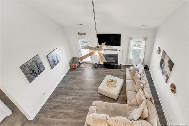 living area featuring wood finished floors, baseboards, and a glass covered fireplace