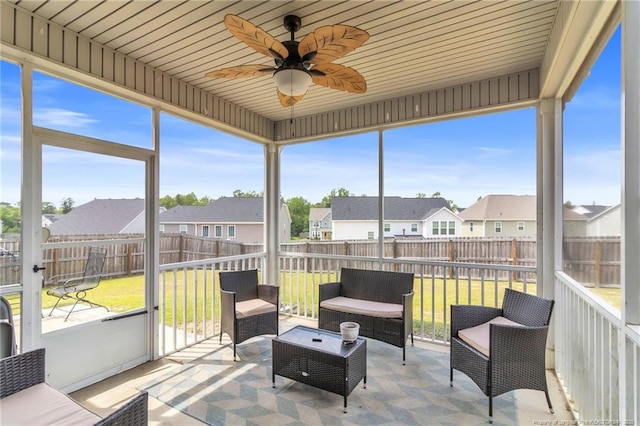 sunroom / solarium featuring a residential view, ceiling fan, and plenty of natural light