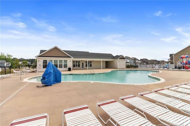 community pool with a patio area and fence