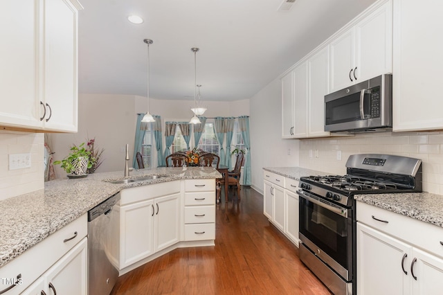 3904 Freemark Ln, Fuquay Varina, NC 27526 - kitchen featuring stainless steel appliances, a sink, a peninsula, wood finished floors, and white cabinetry
