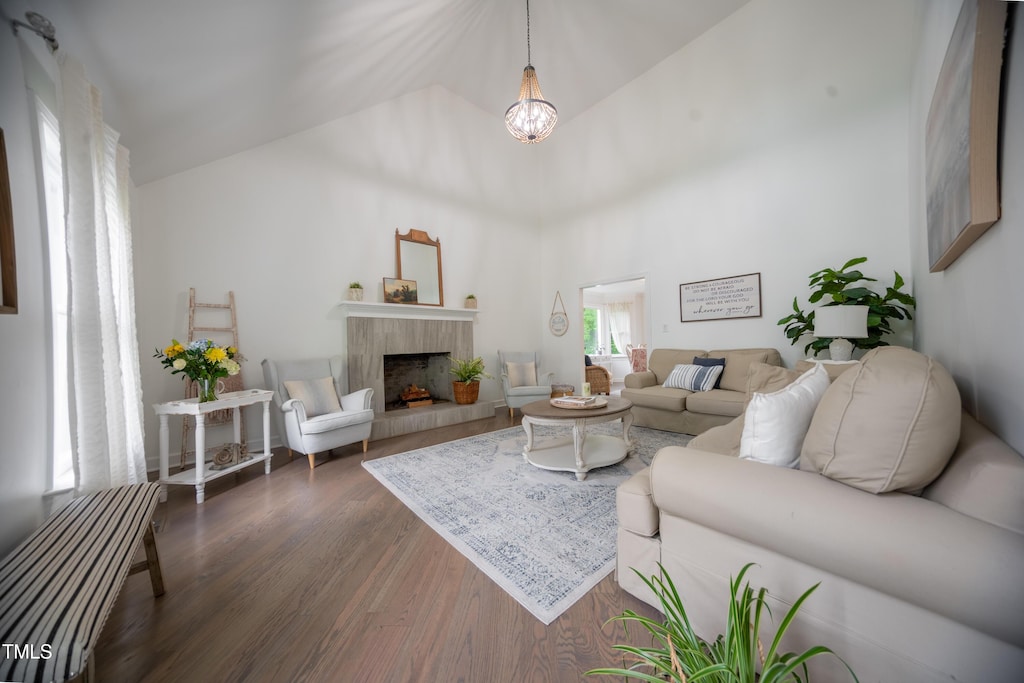 living area with dark wood finished floors, a fireplace, a chandelier, and high vaulted ceiling