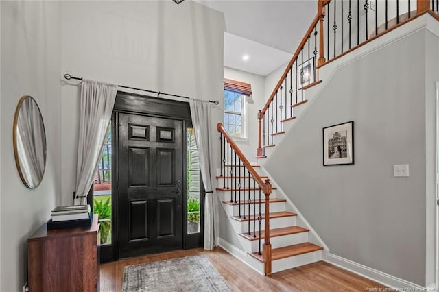 foyer with wood finished floors, stairway, baseboards, and recessed lighting