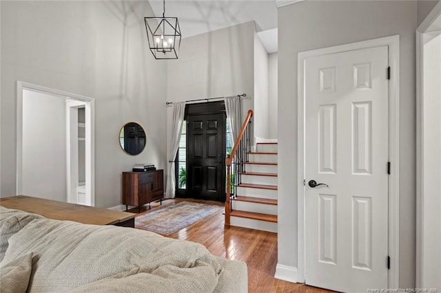 entrance foyer featuring a towering ceiling, light wood-style flooring, stairs, a chandelier, and baseboards
