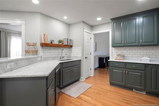 kitchen featuring a sink, open shelves, decorative backsplash, light countertops, and light wood-type flooring