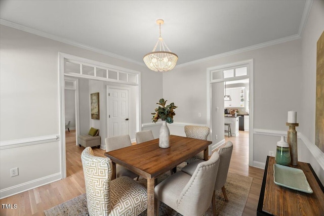 dining area with a chandelier, light wood-type flooring, ornamental molding, and baseboards