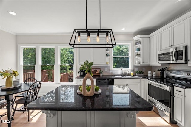 kitchen featuring stainless steel appliances, a sink, crown molding, white cabinets, and a kitchen island