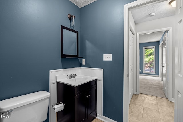 4631 Timbermill Ct Unit 203, Raleigh, NC 27612 - half bath with a textured ceiling, toilet, vanity, baseboards, and tile patterned flooring