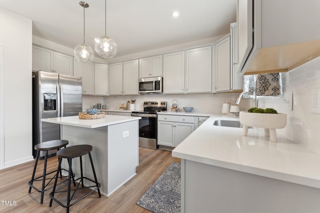 27 Cribbs Ln, Middlesex, NC 27557 - kitchen featuring stainless steel appliances, a kitchen island, a breakfast bar area, light wood-style floors, and decorative backsplash