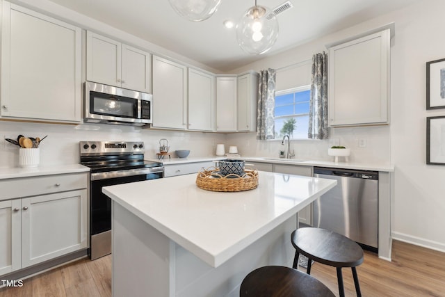 27 Cribbs Ln, Middlesex, NC 27557 - kitchen with stainless steel appliances, a sink, a breakfast bar area, light wood-style flooring, and tasteful backsplash