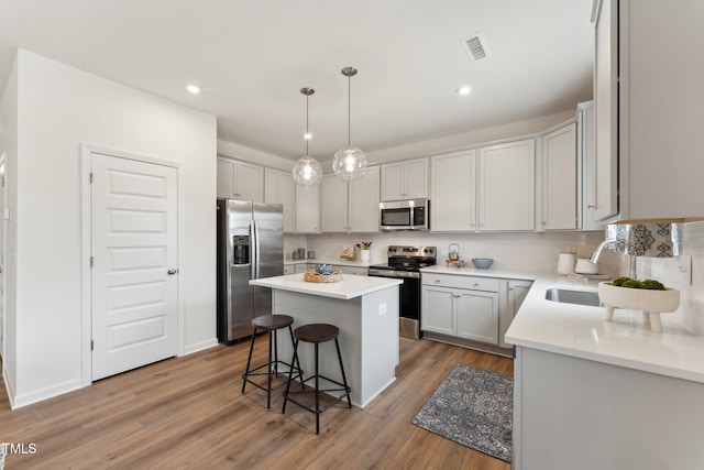 27 Cribbs Ln, Middlesex, NC 27557 - kitchen featuring appliances with stainless steel finishes, a center island, light wood-type flooring, a kitchen bar, and light countertops