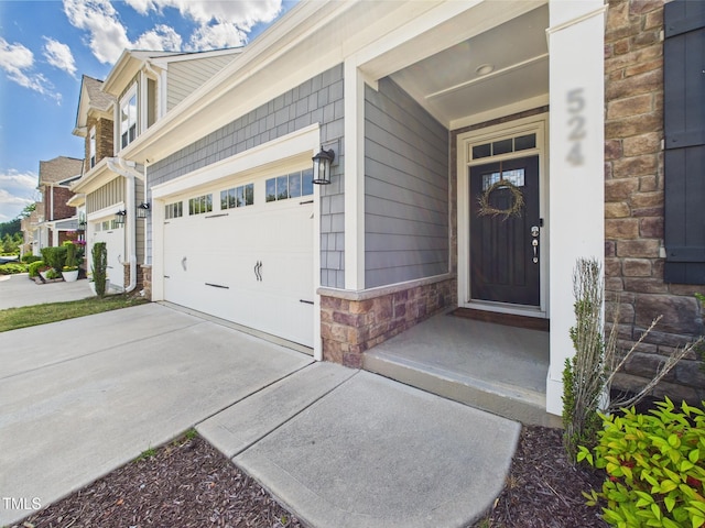 view of exterior entry featuring stone siding, a garage, and driveway