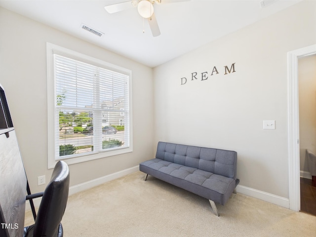 living area featuring carpet floors, baseboards, and a ceiling fan