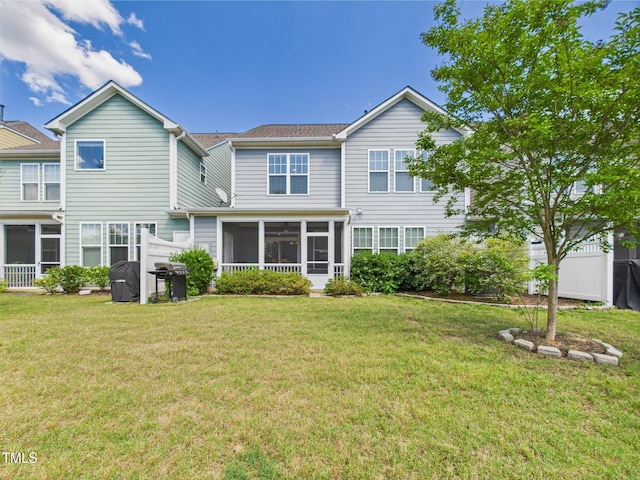 back of property featuring a sunroom and a lawn