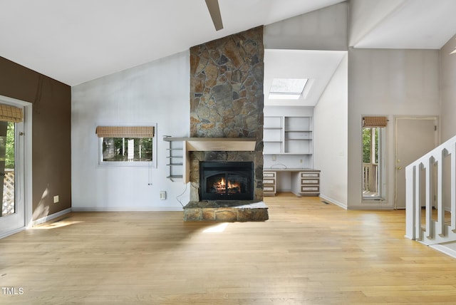 unfurnished living room with high vaulted ceiling, plenty of natural light, a skylight, and light wood-style floors