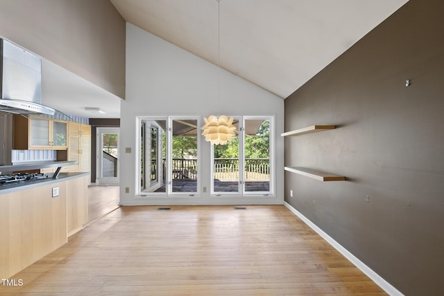 unfurnished living room featuring light wood-style flooring, high vaulted ceiling, and baseboards