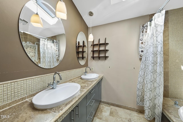 bathroom featuring a tile shower, double vanity, and stone finish floors