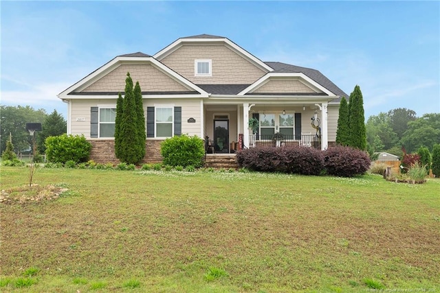 craftsman inspired home featuring covered porch, a front lawn, and stone siding