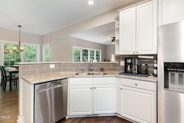 kitchen featuring appliances with stainless steel finishes, a sink, dark wood-type flooring, a ceiling fan, and decorative backsplash
