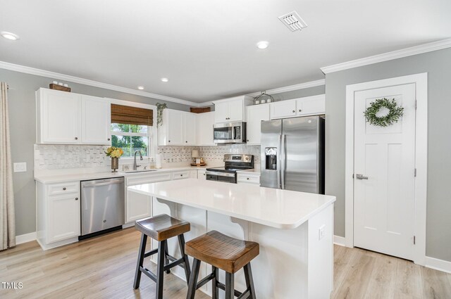 8615 Kenridge Ln, Fuquay Varina, NC 27526 - kitchen featuring stainless steel appliances, a sink, light wood-style floors, tasteful backsplash, and white cabinetry