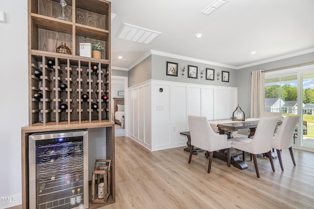 8615 Kenridge Ln, Fuquay Varina, NC 27526 - dining area with beverage cooler, crown molding, wood finished floors, a decorative wall, and recessed lighting