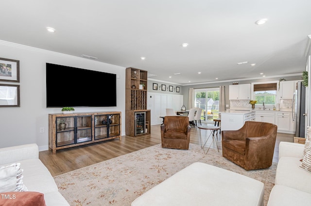 8615 Kenridge Ln, Fuquay Varina, NC 27526 - living area with crown molding, wine cooler, light wood-style floors, recessed lighting, and baseboards