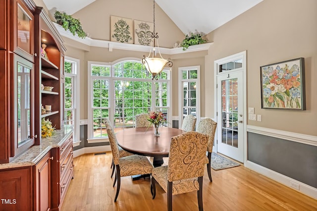 dining area featuring light wood finished floors, high vaulted ceiling, and baseboards