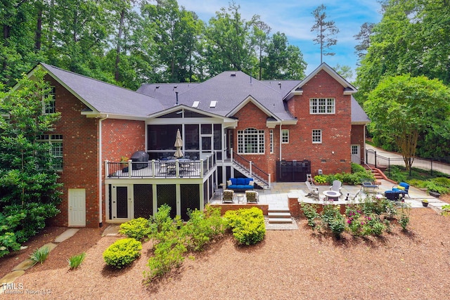 rear view of property with a jacuzzi, stairway, a sunroom, a patio area, and brick siding