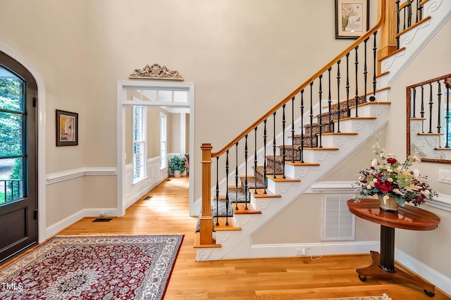 foyer entrance with a high ceiling, wood finished floors, stairway, baseboards, and arched walkways