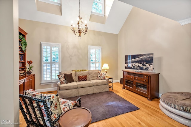 living room with wood finished floors, a chandelier, high vaulted ceiling, a skylight, and baseboards