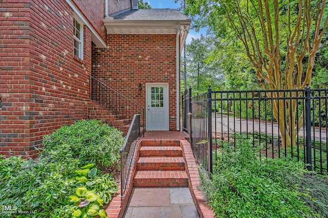 doorway to property featuring fence and brick siding